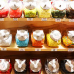 Jars of jelly beans, sorted by color, displayed on 3 shelves 